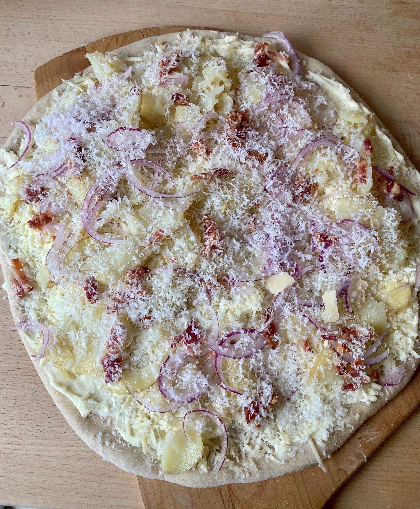 Feature Pizza- Yukon Gold potatoes, local bacon, red onion, bechamel sauce, parmesan, Asiago cheese